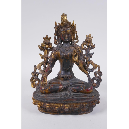 100 - A Sino Tibetan bronze figure of a female deity seated on a lotus throne, with the remnants of gilt a... 