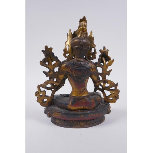 100 - A Sino Tibetan bronze figure of a female deity seated on a lotus throne, with the remnants of gilt a... 