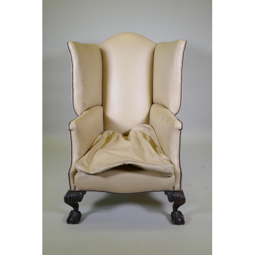 1009 - A Georgian style 'Porter's' leather wing back armchair raised on carved ball and claw supports, 120c... 