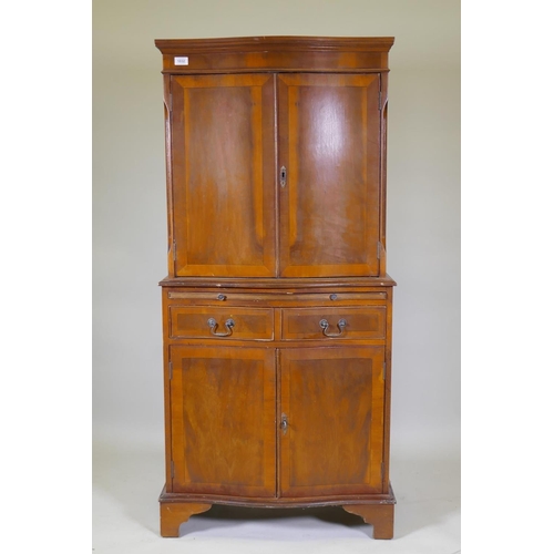 1032 - A serpentine front yew wood cocktail cabinet, with two cupboards and mirror back interior, brushing ... 