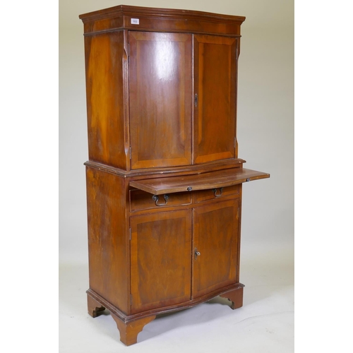 1032 - A serpentine front yew wood cocktail cabinet, with two cupboards and mirror back interior, brushing ... 