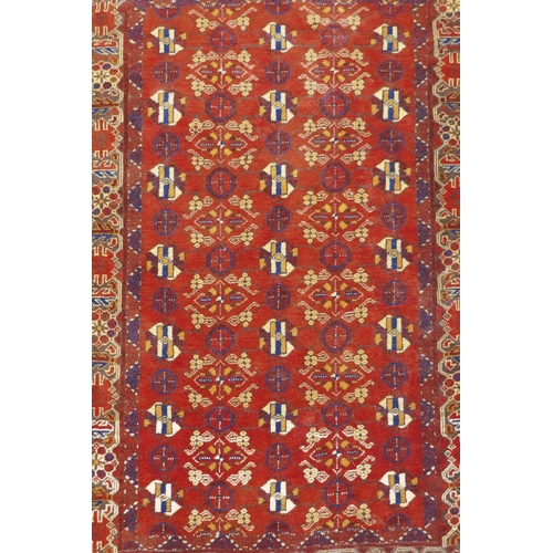 1057 - A Persian red ground wool rug with geometric design, 108 x 148cm