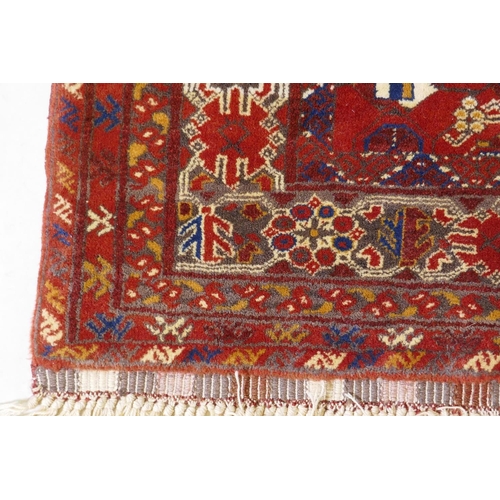 1057 - A Persian red ground wool rug with geometric design, 108 x 148cm