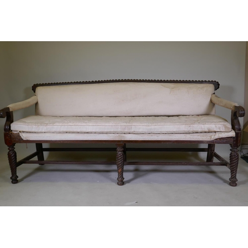 1058 - A C19th Anglo-Indian hardwood settee, with carved gadrooned back and scroll arms, raised on twisted ... 