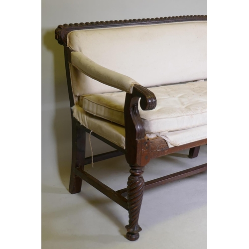 1058 - A C19th Anglo-Indian hardwood settee, with carved gadrooned back and scroll arms, raised on twisted ... 