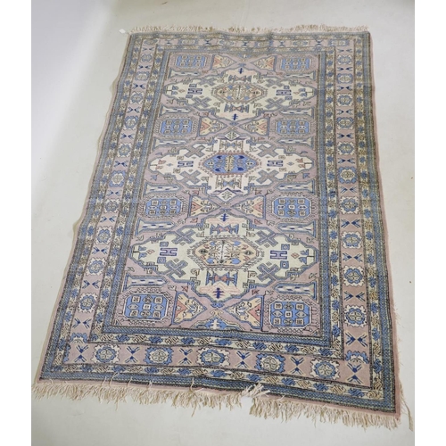 1067 - An antique Persian faded pink ground wool carpet with a green geometric medallion design, 140 x 190c... 