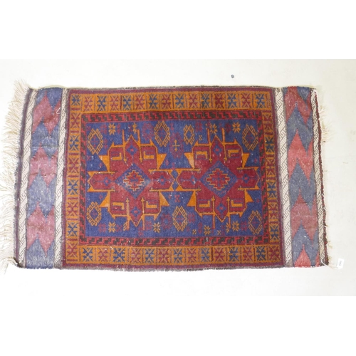 1068 - An antique Persian wool rug with a twin red and orange medallion design on a blue field, 82 x 132cm