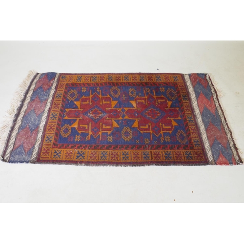 1068 - An antique Persian wool rug with a twin red and orange medallion design on a blue field, 82 x 132cm