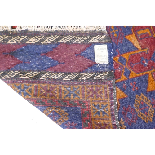 1068 - An antique Persian wool rug with a twin red and orange medallion design on a blue field, 82 x 132cm