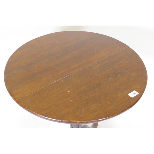 1096 - A Georgian tilt top oak table, raised on a canon barrel turned column with tripod supports, adapted,... 