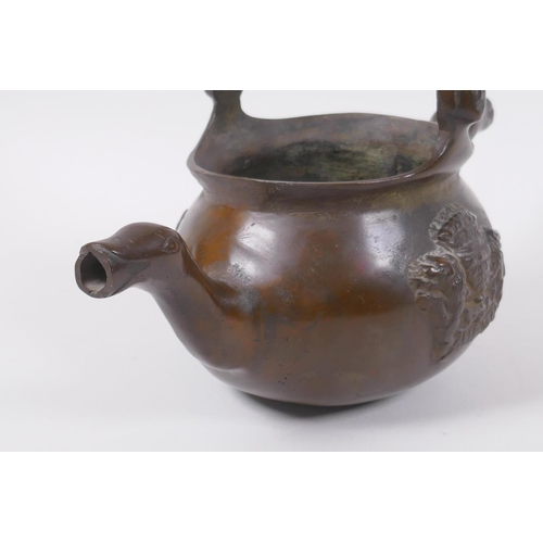 137 - A solid bronze double spouted hanging tea pot with heraldic decoration, 29cm long