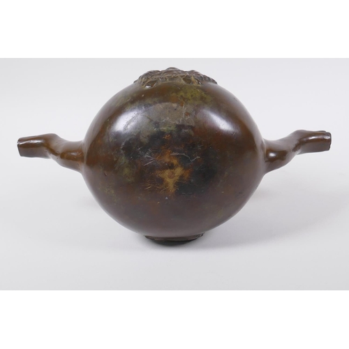 137 - A solid bronze double spouted hanging tea pot with heraldic decoration, 29cm long