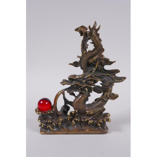 153 - A Chinese filled bronze figure of a dragon and a red glass flaming pearl, impressed seal mark to bas... 