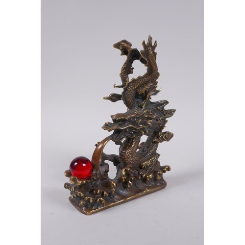 153 - A Chinese filled bronze figure of a dragon and a red glass flaming pearl, impressed seal mark to bas... 