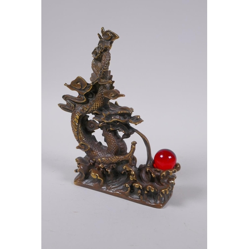 153 - A Chinese filled bronze figure of a dragon and a red glass flaming pearl, impressed seal mark to bas... 