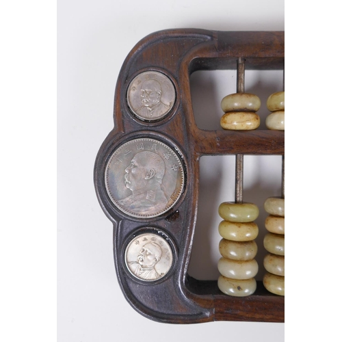 170 - A Chinese hardwood abacus with celadon hardstone counters and inset with facsimile white metal coins... 