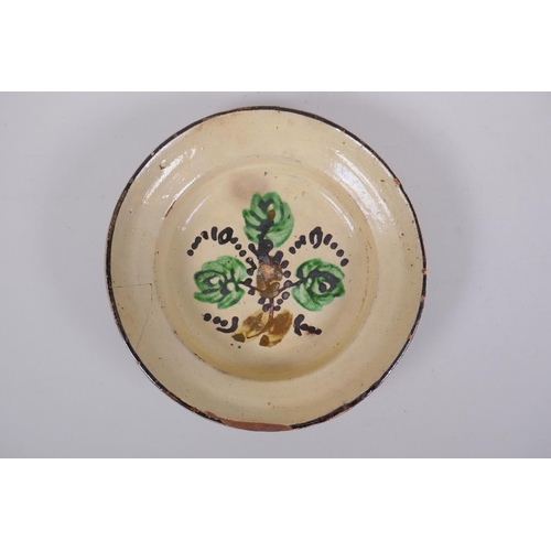 172 - An antique Spanish terracotta dish with a faience glaze and floral decoration, AF repair, 21cm diame... 