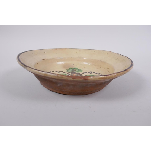 172 - An antique Spanish terracotta dish with a faience glaze and floral decoration, AF repair, 21cm diame... 