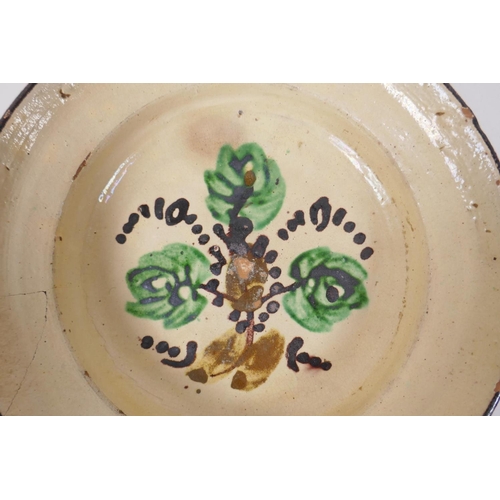 172 - An antique Spanish terracotta dish with a faience glaze and floral decoration, AF repair, 21cm diame... 