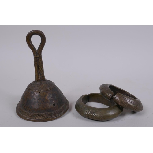 212 - An African Benin bronze bell and two bronze cash bangles, 11cm high