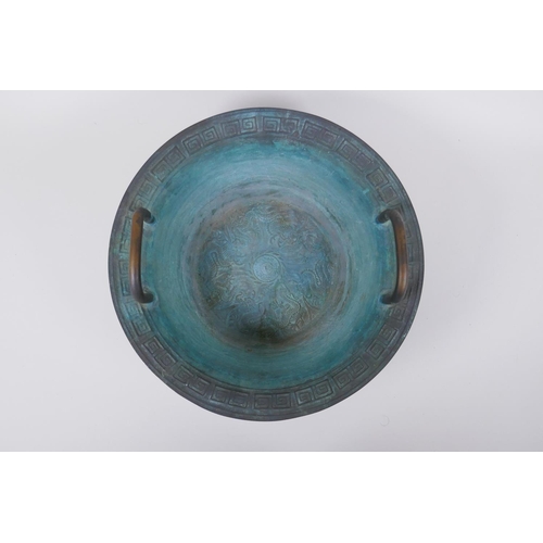 26 - An antique Chinese bronze two handled spouting bowl with dragon decoration, 30cm diameter