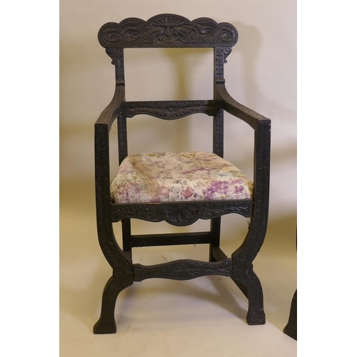 1021 - A pair of C19th ebonised X frame chairs with carved Green Man decoration and drop in seats