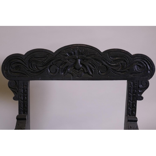 1021 - A pair of C19th ebonised X frame chairs with carved Green Man decoration and drop in seats