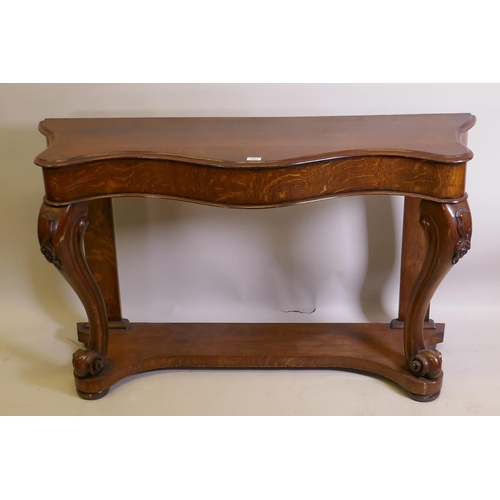 1023 - A Victorian oak serpentine console table on carved scrolled cabriole supports united by an under tie... 