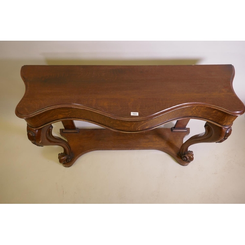 1023 - A Victorian oak serpentine console table on carved scrolled cabriole supports united by an under tie... 