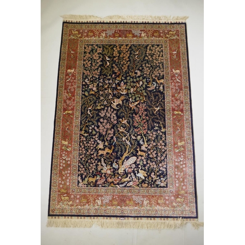 1062 - A Turkish deep blue ground fine woven silk rug with tree of life design and terracotta borders, sign... 