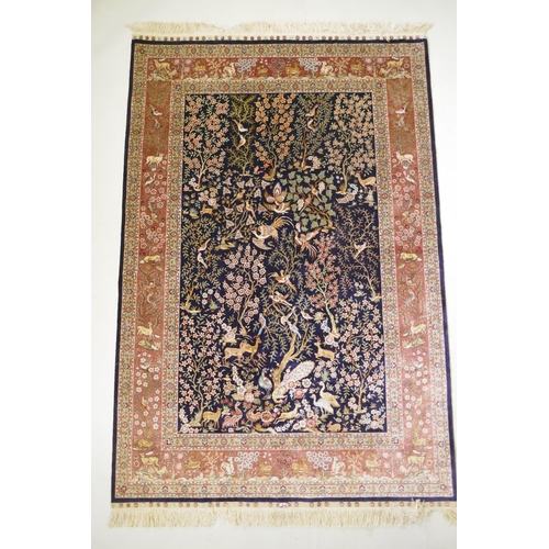 1062 - A Turkish deep blue ground fine woven silk rug with tree of life design and terracotta borders, sign... 