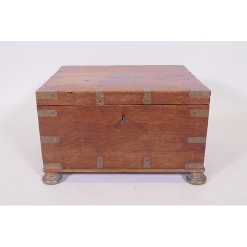 1070 - A C19th teak Anglo Indian vanity chest with campaign style brass mounts and handles, raided on brass... 