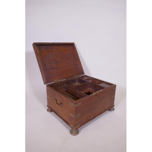 1070 - A C19th teak Anglo Indian vanity chest with campaign style brass mounts and handles, raided on brass... 