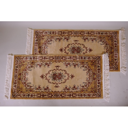 1086 - A pair of gold ground Kashmir runners with a floral medallion design, 142 x 68cm