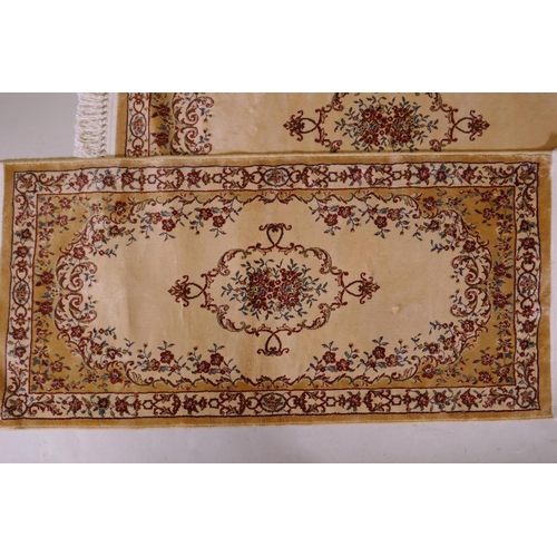 1086 - A pair of gold ground Kashmir runners with a floral medallion design, 142 x 68cm