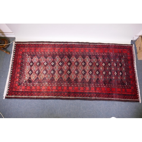 1087 - A full pile hand woven red ground carpet with a geometric floral design, 268 x 130cm