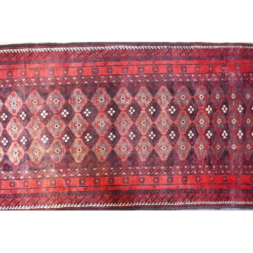 1087 - A full pile hand woven red ground carpet with a geometric floral design, 268 x 130cm