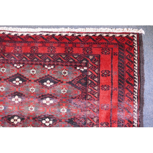 1087 - A full pile hand woven red ground carpet with a geometric floral design, 268 x 130cm