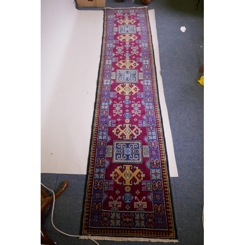 1092 - A claret wine ground wool caucasian runner with bespoke medallion design in unique colours, 322 x 73... 