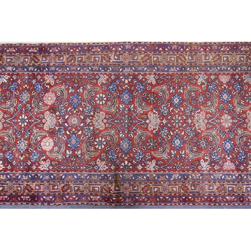 1094 - A hand woven red ground Persian Hamadan nomadic runner with an allover floral design, 102 x 310cm