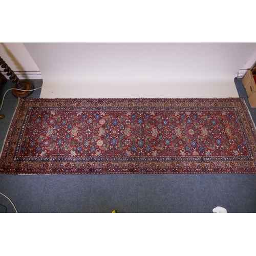 1094 - A hand woven red ground Persian Hamadan nomadic runner with an allover floral design, 102 x 310cm