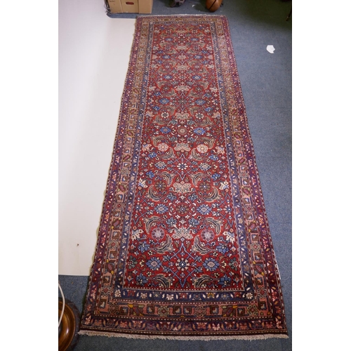 1094 - A hand woven red ground Persian Hamadan nomadic runner with an allover floral design, 102 x 310cm