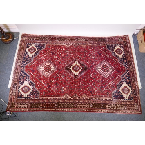 1104 - A hand woven red ground Persian carpet with a unique medallion design and chocolate brown borders, 2... 