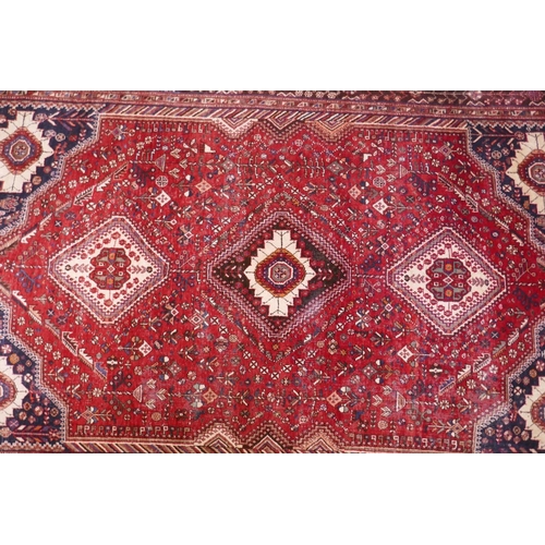 1104 - A hand woven red ground Persian carpet with a unique medallion design and chocolate brown borders, 2... 