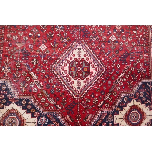 1104 - A hand woven red ground Persian carpet with a unique medallion design and chocolate brown borders, 2... 