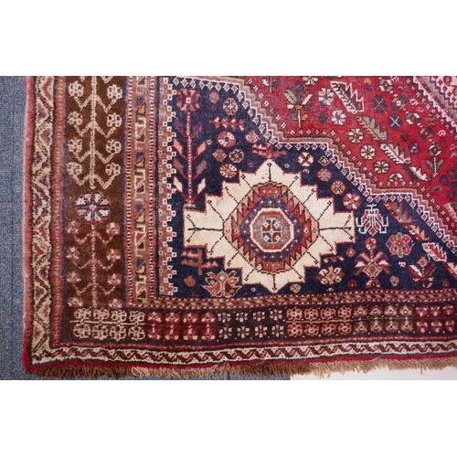 1104 - A hand woven red ground Persian carpet with a unique medallion design and chocolate brown borders, 2... 