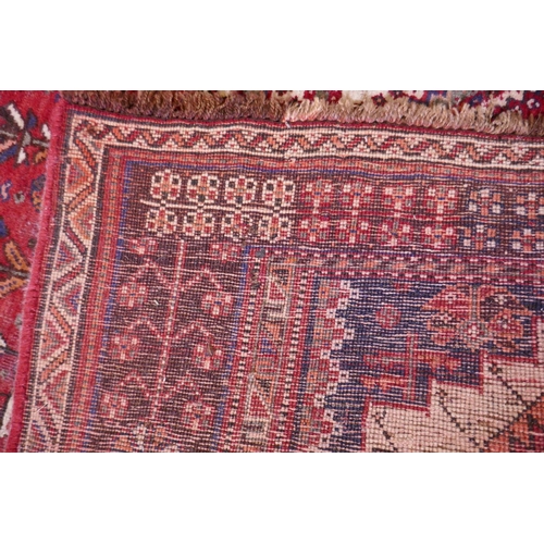 1104 - A hand woven red ground Persian carpet with a unique medallion design and chocolate brown borders, 2... 