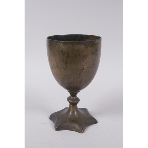 14 - An early Nepalese/Tibetan bronze chalice with a star shaped foot and archaic inscriptions, 17cm high