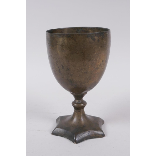 14 - An early Nepalese/Tibetan bronze chalice with a star shaped foot and archaic inscriptions, 17cm high