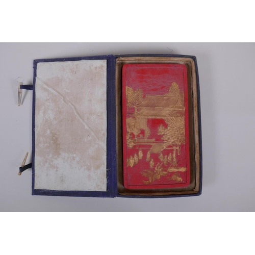 143 - A Chinese red ink stone with raised and gilt decoration of figures in a palace, character marks vers... 